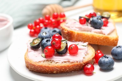 Photo of Tasty sandwiches with cream cheese, berries and honey, closeup