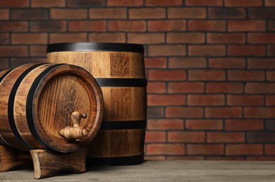 Photo of Wooden barrels on table near brick wall, space for text