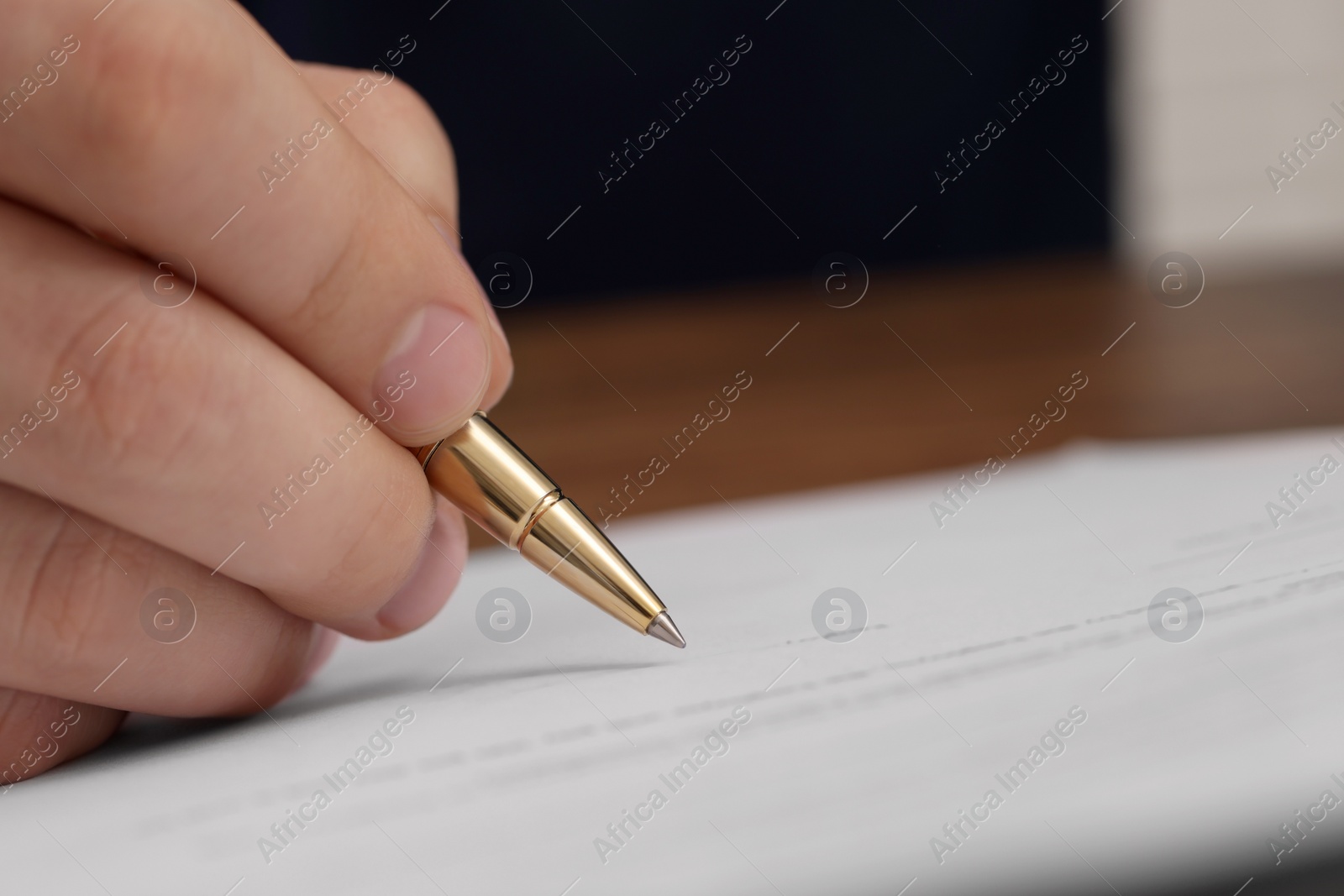 Photo of Man signing document at wooden table, closeup