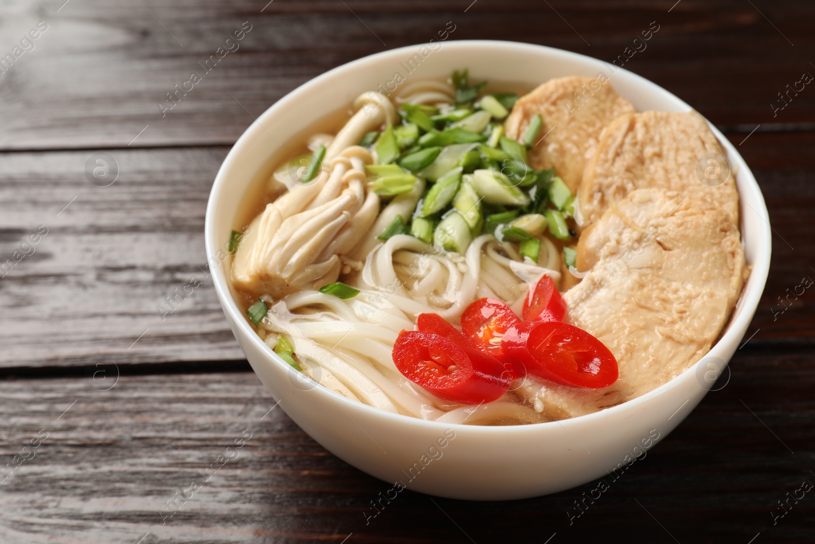 Photo of Delicious ramen with meat and mushrooms in bowl on wooden table, closeup. Noodle soup