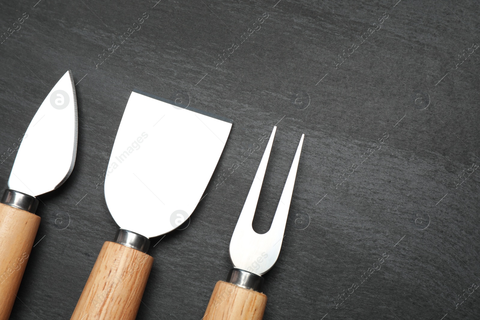 Photo of Cheese knives and fork on black background, flat lay. Space for text