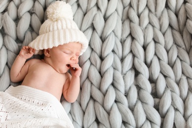 Photo of Adorable newborn baby in warm hat lying on bed, top view