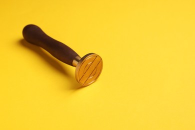 Photo of One stamp tool with wooden handle on yellow background. Space for text