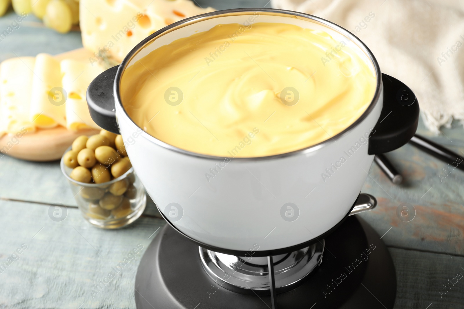 Photo of Pot with delicious cheese fondue on wooden table