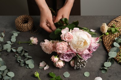 Photo of Florist creating beautiful bouquet at black table indoors, closeup