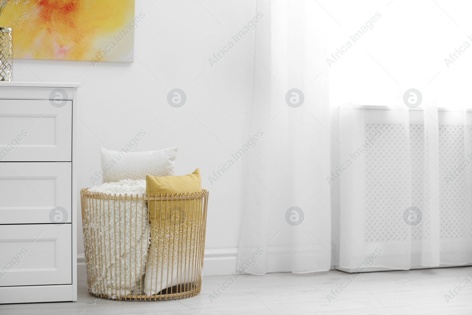 Photo of Basket with soft plaid and pillows in room. Space for text