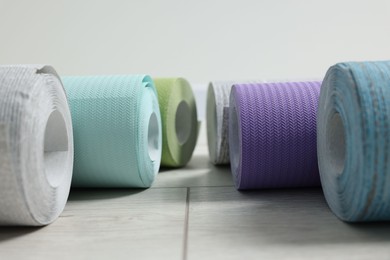 Many different wallpaper rolls on light wooden floor, closeup