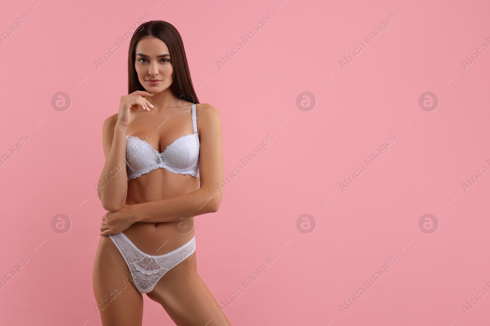 Photo of Young woman in elegant white underwear on pink background. Space for text