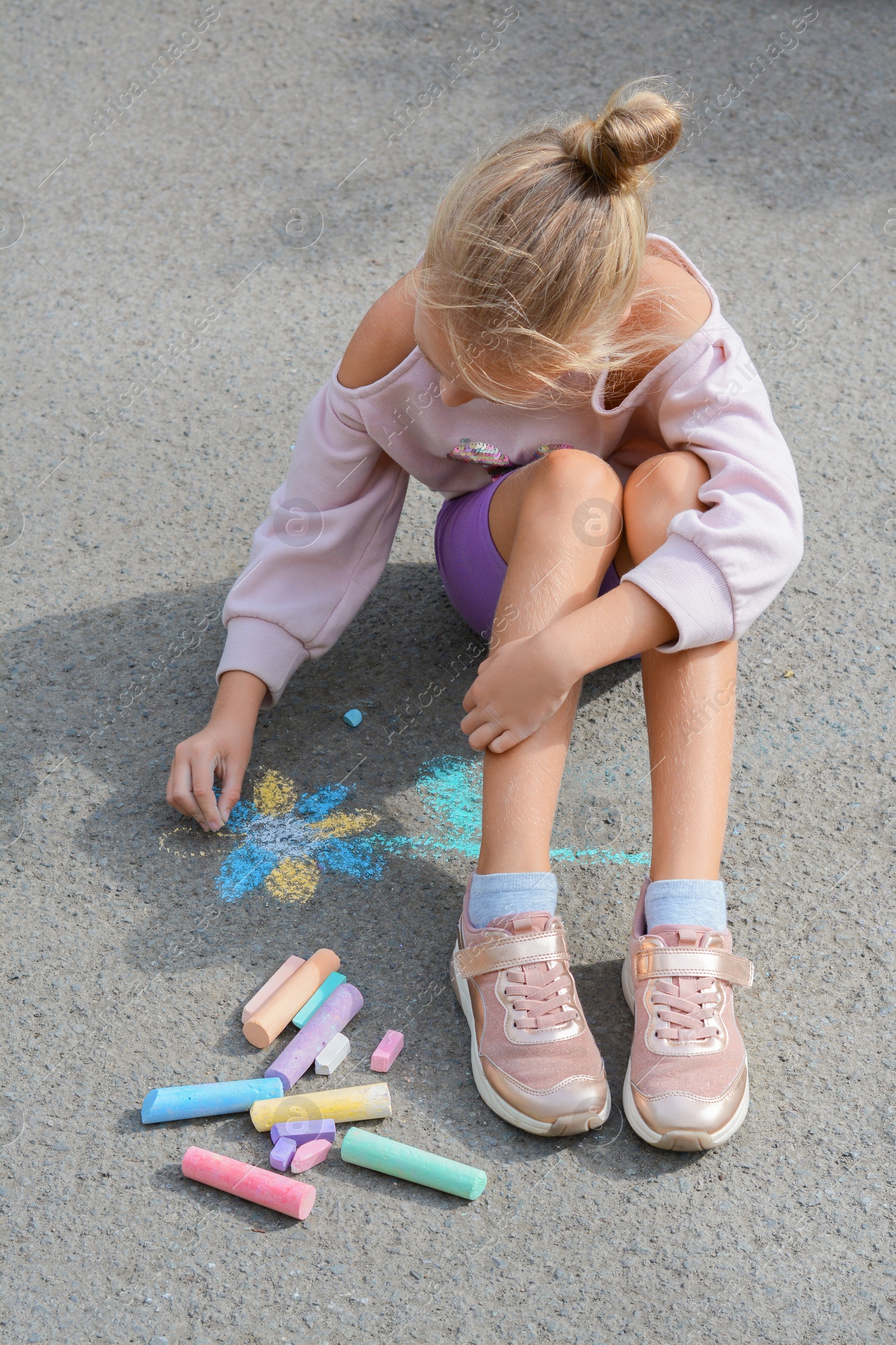 Photo of Little child drawing flower with chalk on asphalt