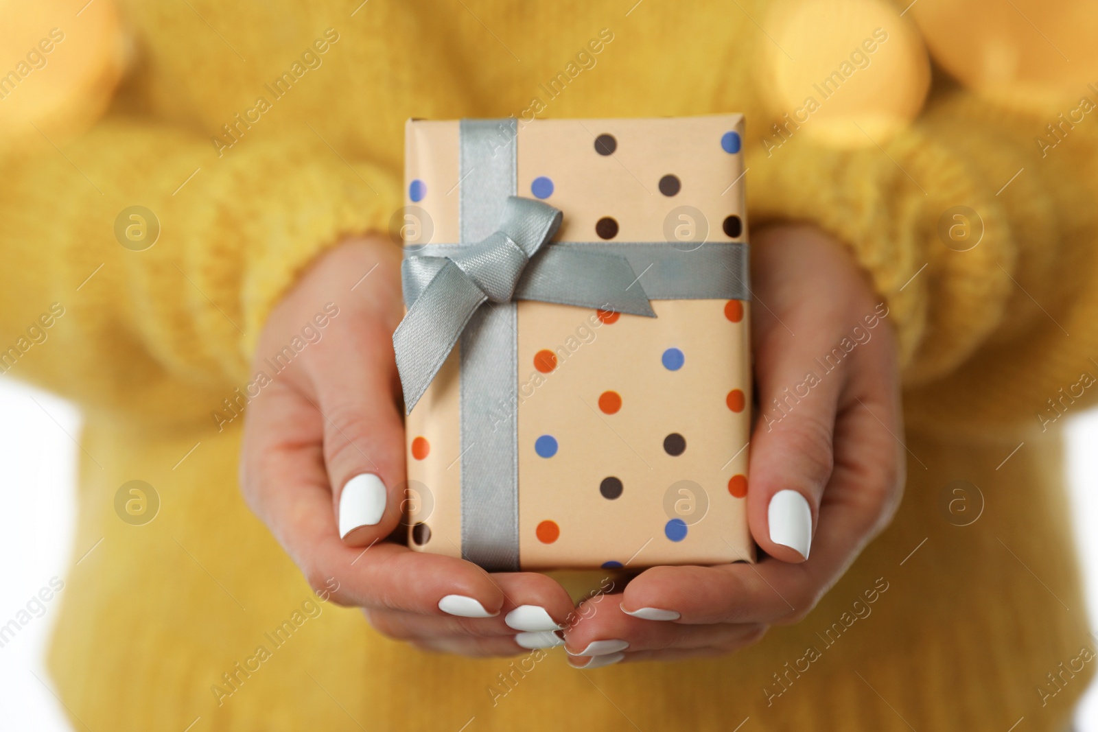 Photo of Woman in warm sweater holding Christmas gift on white background, closeup