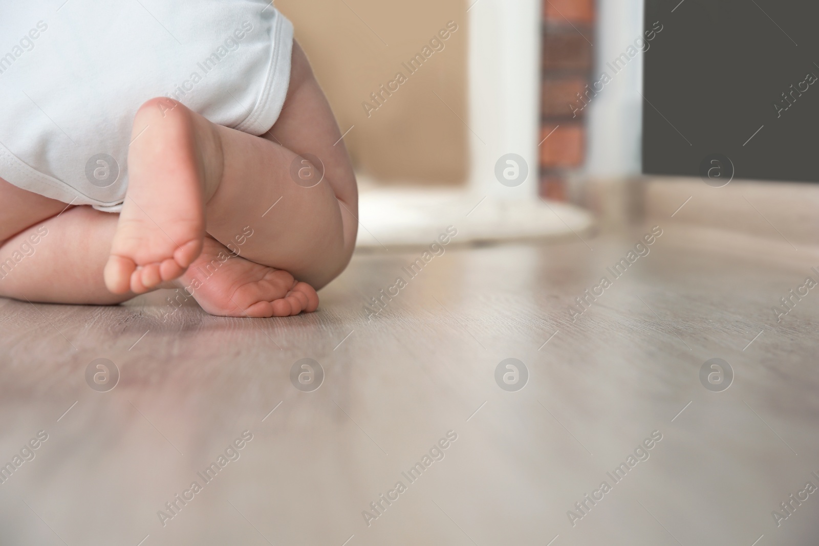 Photo of Cute little baby crawling on floor indoors, closeup with space for text