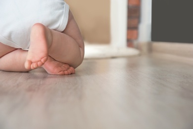 Photo of Cute little baby crawling on floor indoors, closeup with space for text