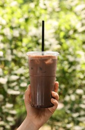 Photo of Woman holding takeaway plastic cup with cold coffee drink outdoors, closeup