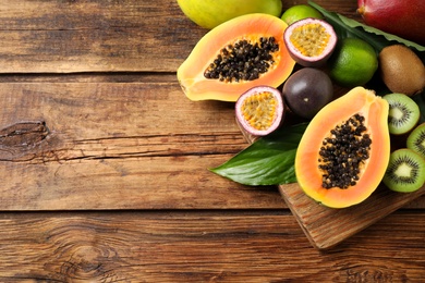 Photo of Fresh ripe papaya and other fruits on wooden table, flat lay. Space for text