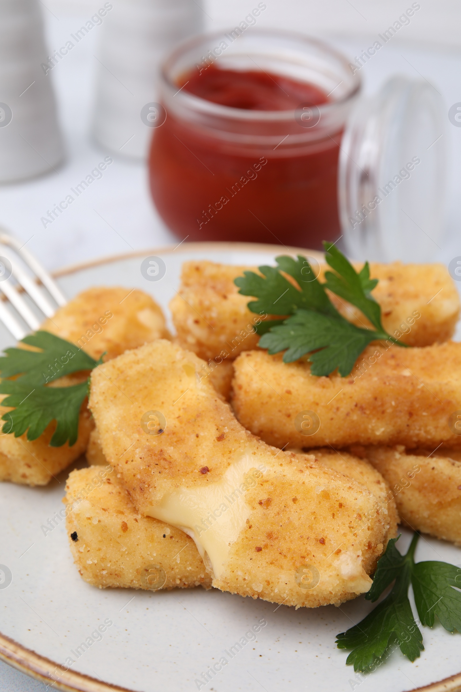 Photo of Plate with tasty fried mozzarella sticks and parsley on table, closeup