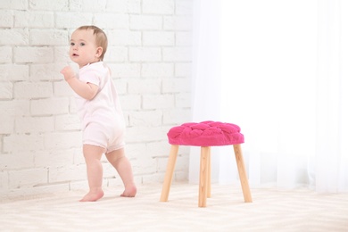Cute baby holding on to wall indoors. Learning to walk