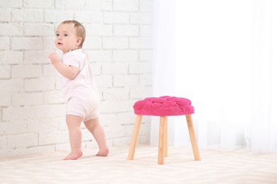 Photo of Cute baby holding on to wall indoors. Learning to walk