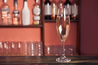 Photo of Glass of champagne on wooden counter in bar