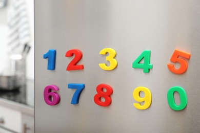 Photo of Colorful magnetic numbers on refrigerator door indoors