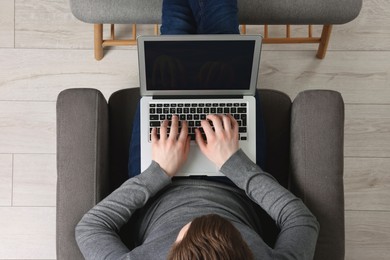 Photo of Man working with laptop in armchair, top view