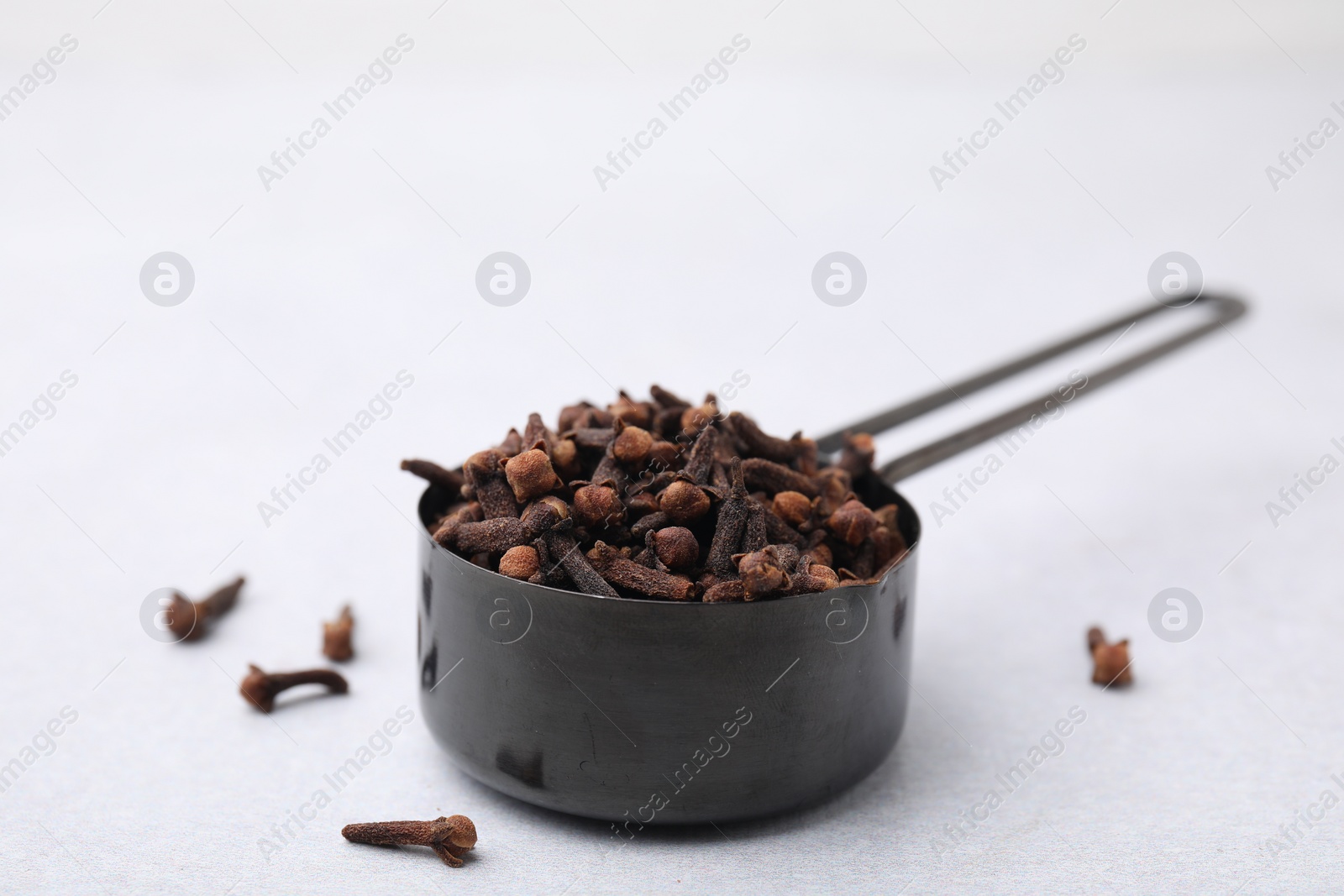 Photo of Aromatic cloves in scoop on light table, closeup