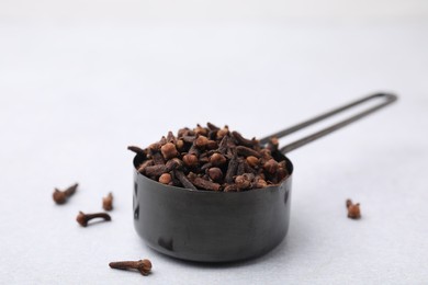 Photo of Aromatic cloves in scoop on light table, closeup