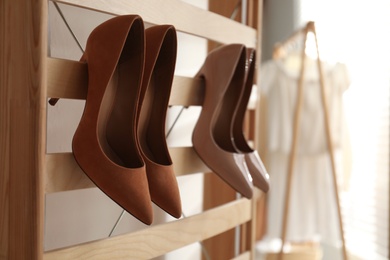 Photo of Rack with stylish women's high heeled shoes in dressing room. Modern interior design