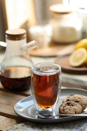 Photo of Glass of delicious tea and cookies on wooden table