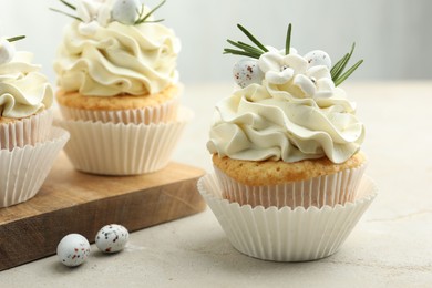 Photo of Tasty Easter cupcakes with vanilla cream and candies on gray table