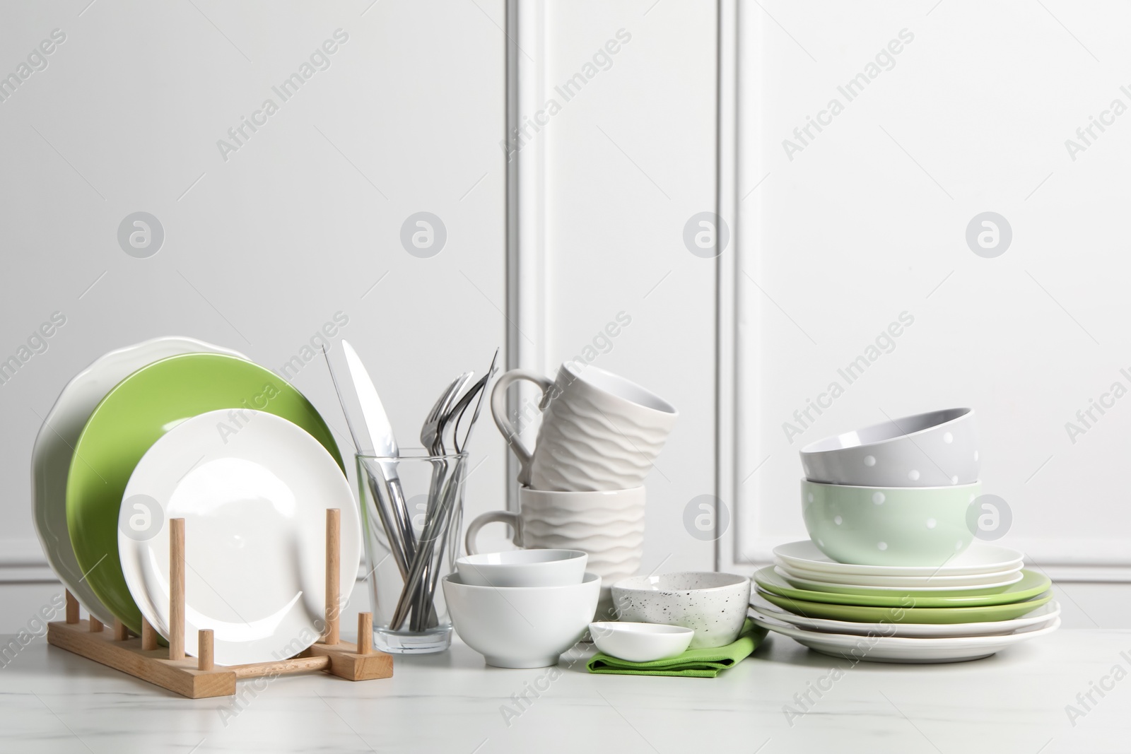 Photo of Beautiful ceramic dishware, cups and cutlery on white marble table