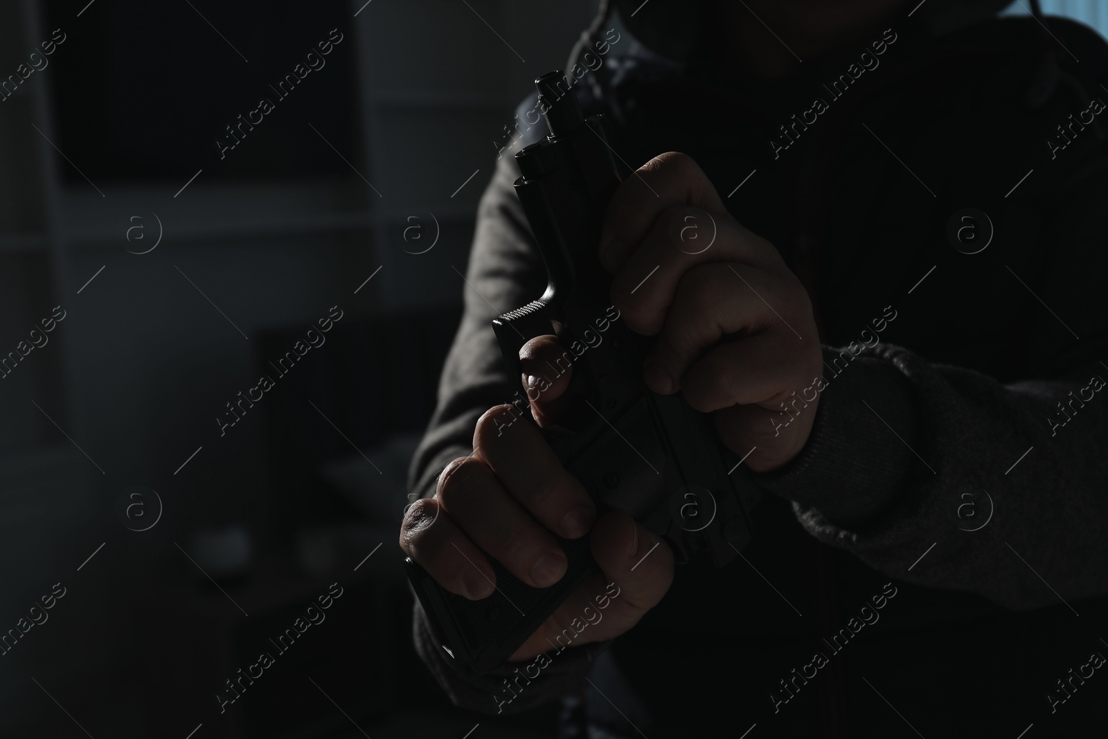 Photo of Dangerous criminal with gun in foreign house, closeup. Armed robbery