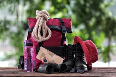 Photo of Composition with backpack and camping equipment on table against blurred background