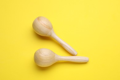 Photo of Wooden maracas on yellow background, flat lay. Musical instrument