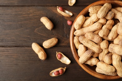 Bowl with peanuts in shell and space for text on table, top view