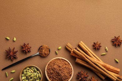 Photo of Cinnamon sticks, star anise and cardamom pods on brown background, flat lay. Space for text
