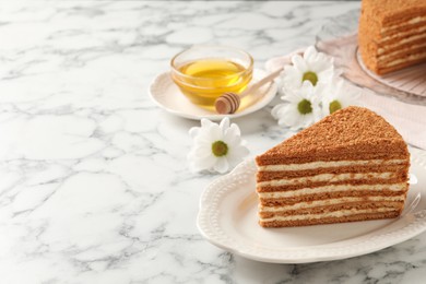 Photo of Slice of delicious layered honey cake served on white marble table. Space for text