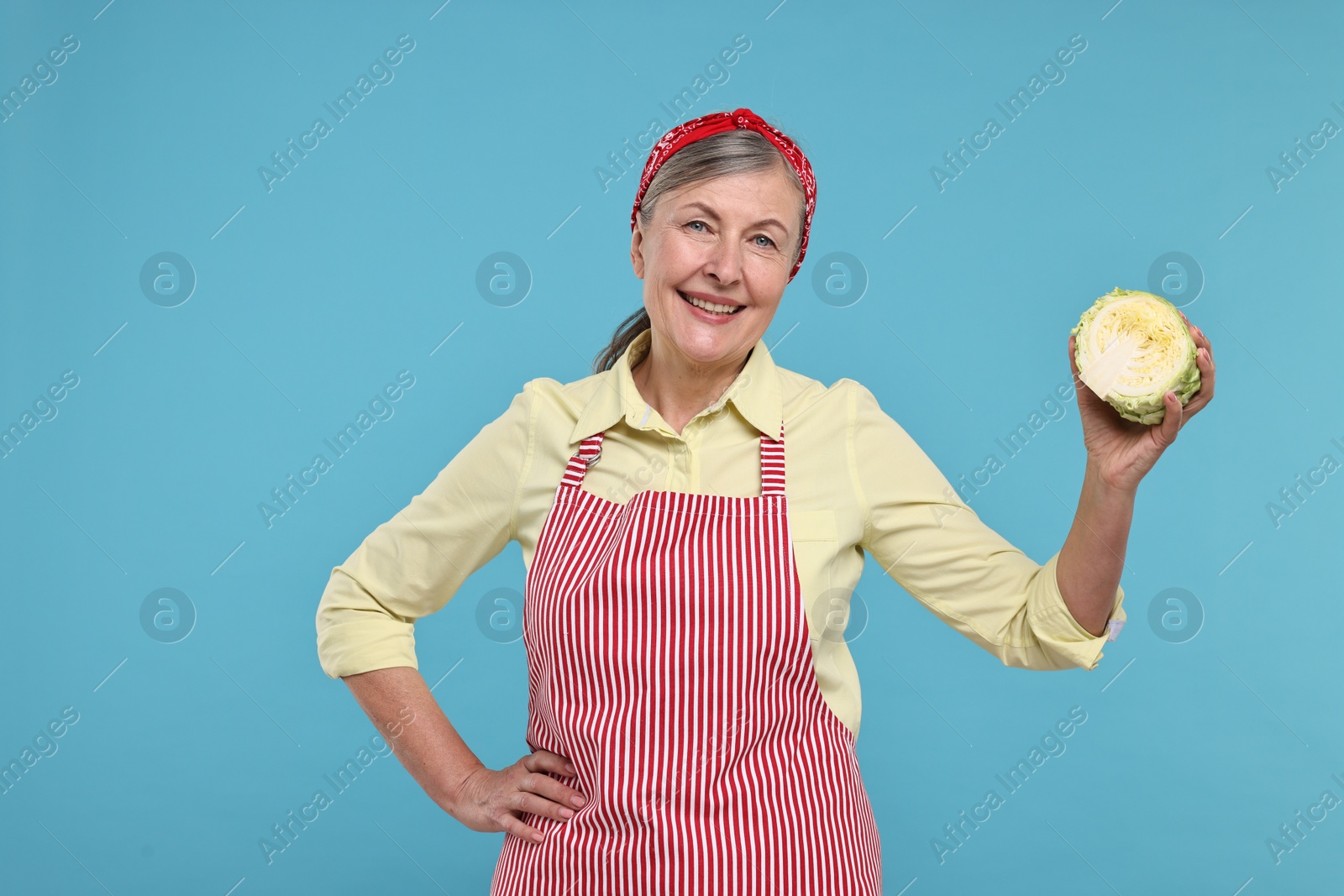Photo of Happy housewife with half of cabbage on light blue background