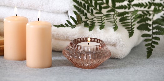 Photo of Spa composition. Burning candles and towels on soft grey surface