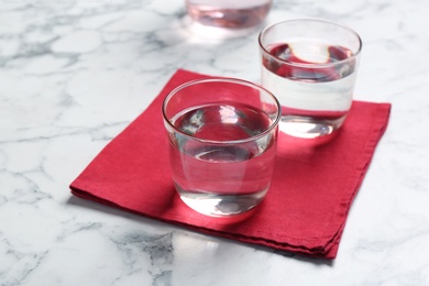 Photo of Glasses with fresh water and napkin on marble table