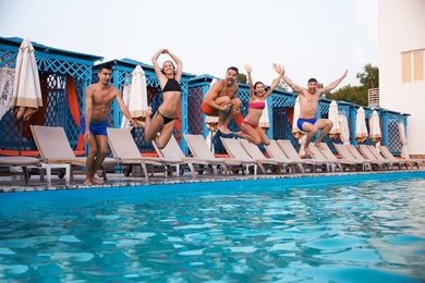 Happy young friends jumping in swimming pool