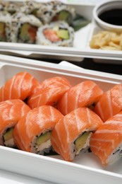 Photo of Delicious sushi rolls in plastic containers, closeup. Food delivery