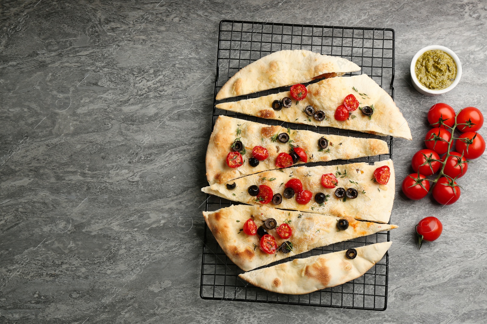 Photo of Delicious focaccia bread with olives and tomatoes on grey table, flat lay. Space for text