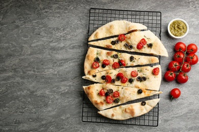 Delicious focaccia bread with olives and tomatoes on grey table, flat lay. Space for text