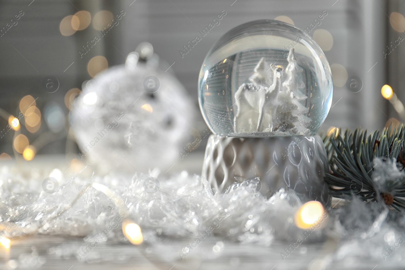 Photo of Christmas glass globe with artificial snow on table against blurred background. Space for text