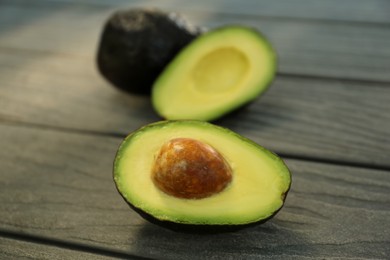 Photo of Half and whole fresh avocados on wooden table, closeup