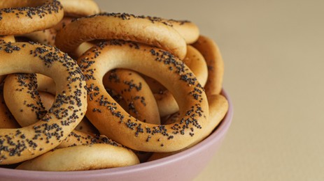 Bowl with delicious ring shaped Sushki (dry bagels) on beige background, closeup. Space for text