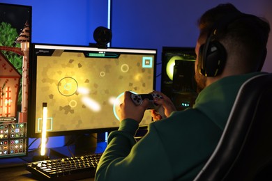 Photo of Man playing video games with controller at table indoors