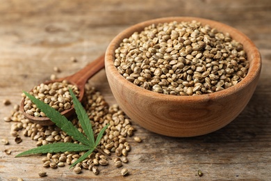 Photo of Organic hemp seeds and leaf on wooden table