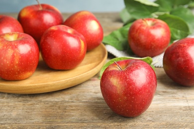 Photo of Ripe juicy red apples on wooden table against blue background