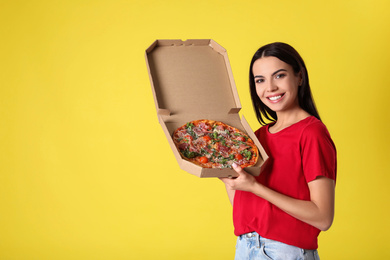 Beautiful woman with tasty pizza on yellow background